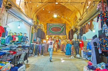 SHIRAZ, IRAN - OCTOBER 14, 2017: The medieval alleyway of Vakil bazaar with clothes stores and...