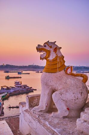 The small Chinthe lion sits on the edge of the hill, overlooking Irrawaddy river on blue hour, Shwe Kyat Kya Pagoda, Mandalay, Myanmarの写真素材