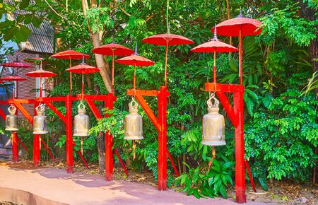 The line of ritual bells, decorated with traditional red umbrellas and located in garden of Wat Phan Tao, Chiang Mai, Thailandの写真素材