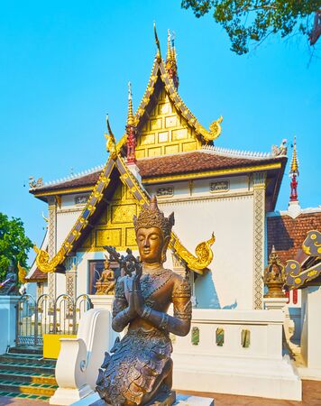 The scenic bronze Devata (deity) sculpture in front of the medieval temple of Sao Inthakin (City Pillar), Wat Chedi Luang, Chiang Mai, Thailandの写真素材