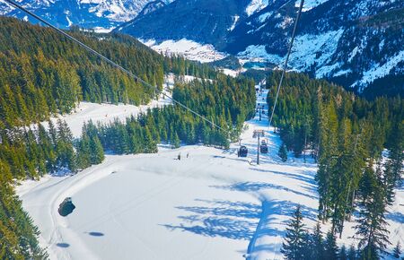 The gondola of air lift rides over the tiny frozen lake, located on slope of Zwieselalm mountain,...