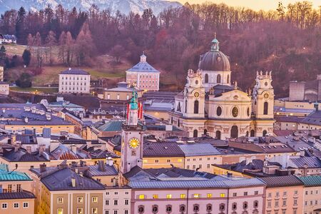 The medieval town of Salzburg with clock tower of the old town hall and huge Kollegienkirche (Collegiate Church) on the background, Austriaの写真素材