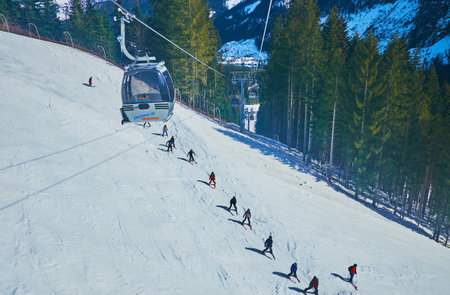 GOSAU, AUSTRIA - FEBRUARY 26, 2019: Panorama Jet Zwieselalm cable car rides over the ski run, full of sportsmen, on February 26 in Gosauのeditorial素材