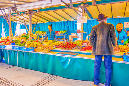 SALZBURG, AUSTRIA - FEBRUARY 27, 2019: The old man choses fruits at the grocery stall in Grunmarkt (Green Market) in University square in Altstadt, on February 27 in Salzburgのeditorial素材