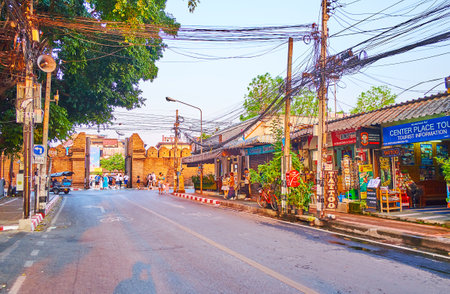 CHIANG MAI, THAILAND - MAY 2, 2019: Walk the street of old town with a view on small shops, cafes, tangled wires over the road and historical Tha Pae Gate of old town fortress on background, on May 2 in Chiang Maiのeditorial素材