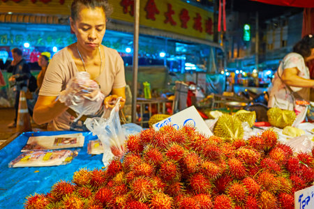 CHIANG MAI, THAILAND - MAY 2, 2019: The small street stall of Warorot Night Market offers tasty tropical rambutan fruits, on May 2 in Chiang Maiのeditorial素材