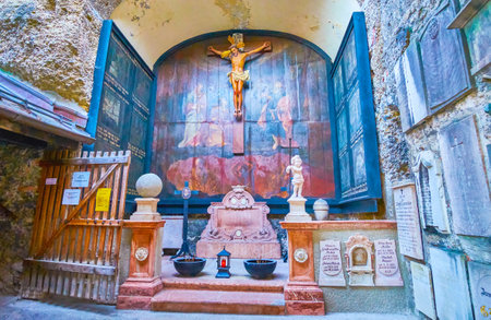 SALZBURG, AUSTRIA - FEBRUARY 27, 2019: The small chapel in catacombs of Sr.Peter cemetery with old wooden painted altarpiece and carved tombstones on the walls, on February 27 in Salzburgのeditorial素材