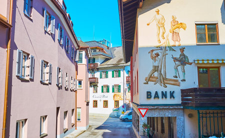 ST GILGEN, AUSTRIA - FEBRUARY 23, 2019: The narrow street of St Gilgen tourist village with traditional Alpine edifices, decorated with wooden shutters and vintage images and inscriptions, on February 23 in St Gilgenのeditorial素材