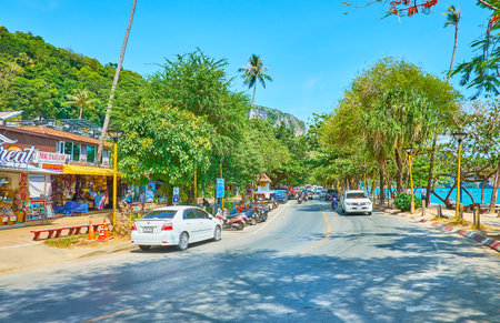 AO NANG, THAILAND - APRIL 25, 2019: The busy road along the beach with driving cars, tuk-tuks, line of lush trees, tourist shops and cafes, on April 25 in Ao Nangのeditorial素材