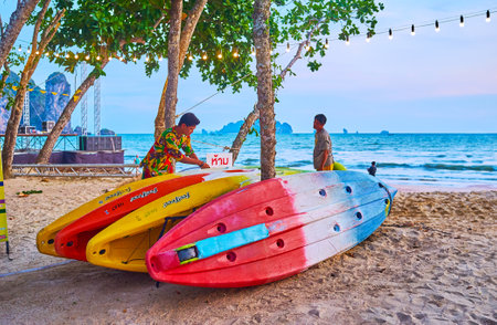 AO NANG, THAILAND - APRIL 25, 2019: The colorful boats for rent on the beach, next to the lounge cafes and bars, on April 25 in Ao Nangのeditorial素材