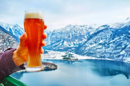 Enjoy the glass of beer in outdoor terrace of the restaurant, located on top of Salzberg mount and observing snowy Alps and Hallstattersee lake, Hallstatt, Salzkammergut, Austriaの写真素材