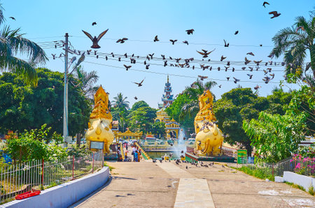 YANGON, MYANMAR - FEBRUARY 17, 2018: The flock of flying pigeons above the garden of Maha Wizaya (Mahavijaya) Pagoda with statues of chinthe lions, on February 17 in Yangonのeditorial素材