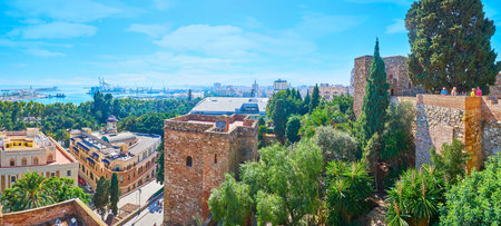MALAGA, SPAIN - SEPTEMBER 26, 2019: Tall stone towers of Alcazaba fortress with lush garden amid the ramparts and cross shaped Torre del Cristo (Crist's gate) in the middle, on September 26 in Malagaのeditorial素材