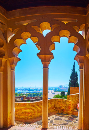 The view on the open air terrace of Alcazaba fortress through the carved stone pass in corridor of Nasrid (Palacio Nazari) palace, Malaga, Spainのeditorial素材