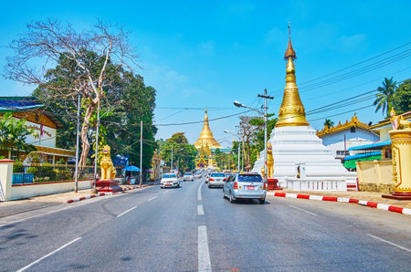 YANGON, MYANMAR - FEBRUARY 17, 2018: Walk along the Tant Taw Mu Pagoda with white-gilt stupa and chinthe lion statues to the South Gate of Shwedagon Zedi Daw, on February 17 in Yangonのeditorial素材