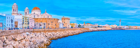 CADIZ, SPAIN - SEPTEMBER 19, 2019: Evening Campo del Sur avenue with a view on historical housing, ramparts, Cathedral, medieval Santa Cruz Church and coast of Atlantic Ocean, on September 19 in Cadizのeditorial素材