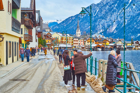 HALLSTATT, AUSTRIA - FEBRUARY 21, 2019: Walk the crowded lakeside promenade of Hallstattersee and enjoy main town landmarks and Alpine landscape, on February 21 in Hallstattのeditorial素材