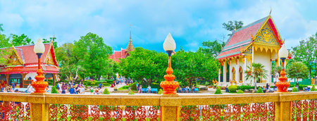 CHALONG, THAILAND - APRIL 30, 2019: Panorama of Wat Chaiyathararam (Wat Chalong) temple with ornate shrines, shady green garden and lace-like fence on the foreground, on April 30 in Chalongのeditorial素材