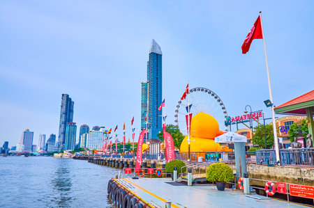 BANGKOK, THAILAND - APRIL 15, 2019: The view from the pier on the large promenade of Asiatique park with restaurants in old docks and large sculptures of yellow bath ducks, on April 15 in Bangkokのeditorial素材