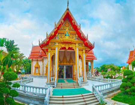 CHALONG, THAILAND - APRIL 30, 2019: The rich exterior decoration of the shrines of Wat Chalong temple with carved bargeboards, pyathat roof, gilt patterns, mirror mosaic and sculpture of Deva in the middle, on April 30 in Chalongのeditorial素材