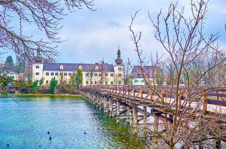 The beautiful wooden bridge leads to the Orth Landschloss casle, located on the bank of Traun lake, that is one of the main landmark of Gmunden town, Austriaのeditorial素材