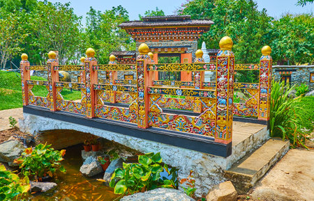 The richly decorated carved wooden bridge with floral and animalistic elements, traditional Thai and Bhutanese flowers of golden shower and blue poppy in Bhutan garden, Rajapruek park, Chiang Mai, Thailandのeditorial素材