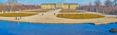 VIENNA, AUSTRIA - FEBRUARY 19, 2019: Panorama with Schonbrunn palace and garden (Shlosspark, Bundesgarten) and clear surface of Neptune fountain's pond on the foreground, on February 19 in Viennaのeditorial素材