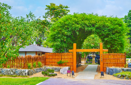 The wooden gate of Japan garden with inscription, translated as "Japanese garden", bamboo fence and lush bamboo arch on the background, Rajapruek park, Chiang Mai, Thailandのeditorial素材