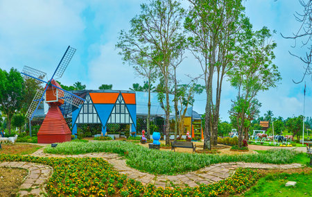 CHIANG MAI, THAILAND - MAY 7, 2019: Panorama of Netherlands garden of Rajapruek park with flower beds, green lawn, tall trees, red windmill, colorful pavilion and installations, on May 7 in Chiang Maiのeditorial素材