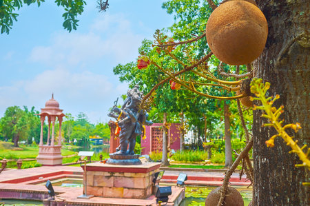 The view on Ganesha statue and red mondop pavilion through the branches and fruit of cannonball tree, India garden, Rajapruek park, Chiang Mai, Thailandのeditorial素材
