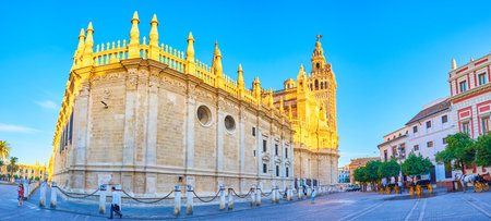 SEVILLE, SPAIN - OCTOBER 1, 2019: Panoramic view on the side walls of the Cathedral and tourist carriages standing along the buildings on Plaza del Triunfo, on October 1 in Sevilleのeditorial素材