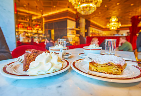 VIENNA, AUSTRIA - FEBRUARY 19, 2019: Delicious chocolate Sacher cake (Sachertorte) and apple strudel with whipped cream in splendid Sacher cafe -popular Wiener coffee house, on February 19 in Viennaのeditorial素材