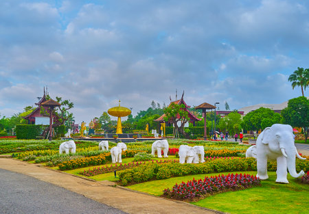CHIANG MAI, THAILAND - MAY 7, 2019: The sculptures of white elephants among the flower beds of Rajapruek park with golden tree installation on background, on May 7 in Chiang Maiのeditorial素材