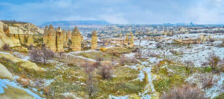 The winter garden in snowy valley of Goreme with bright yellow fairy chimney rocks on background, Cappadocia, Turkeyの写真素材