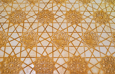 GRANADA, SPAIN - SEPTEMBER 25, 2019: Close-up of sebka plasterwork with stellar patterns and Arabic calligraphy on wall of Patio of Gilded Room (Nasrid Palace, Alhambra), on September 25 in Granadaのeditorial素材