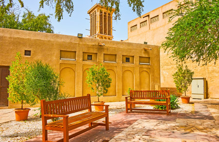 Relax in small shady park with wooden benches, located in old Al Fahidi district with adobe housing and barjeel windcatchers, Dubai, UAEのeditorial素材