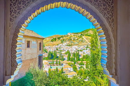 The horseshoe arch of Palace of Lions of Alhambra opens the view on the hilly landscape of Granada, its old districts of Albaicin and Sacromonte, Spainのeditorial素材
