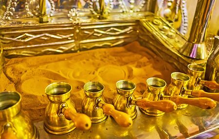 The oven with hot sand and different sized vintage brass cezve coffee pots for making Turkish coffeeの写真素材