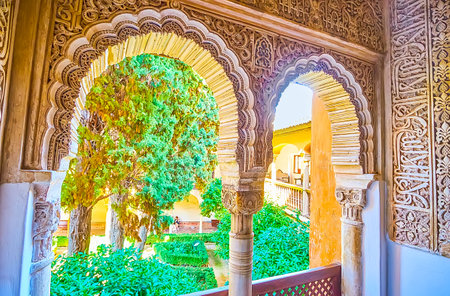 GRANADA, SPAIN - SEPTEMBER 25, 2019: The complex carved arched windows in Palace of Lions (Nasrid Palace, Alhambra) open the view on lush green Daraxa's Garden, on September 25 in Granadaのeditorial素材