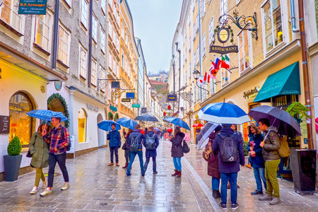 SALZBURG, AUSTRIA - MARCH 1, 2019: The activity during rainy day in Getreidegasse, the popular shopping street in old town, on March 1 in Salzburgのeditorial素材