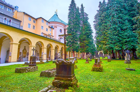 SALZBURG, AUSTRIA - MARCH 1, 2019: The small graveyard of St Sebastian Cemetery with lines of ramshackle graves and high coniferous trees, on March 1 in Salzburgのeditorial素材