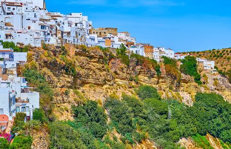 The white housing of Arcos on the edge of the rocky cliff, covered with green vegetation, Spainの写真素材