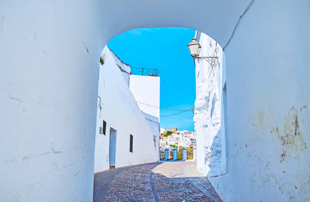 The view on the narrow curved street of Arcos through the small white passage of Martera gate, Spainのeditorial素材