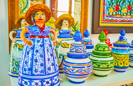 ARCOS, SPAIN - SEPTEMBER 23, 2019: The colorful statuettes, jars, bowls, mugs and cups with primitive floral patterns in store of traditional Andalusian pottery, on September 23 in Arcosのeditorial素材