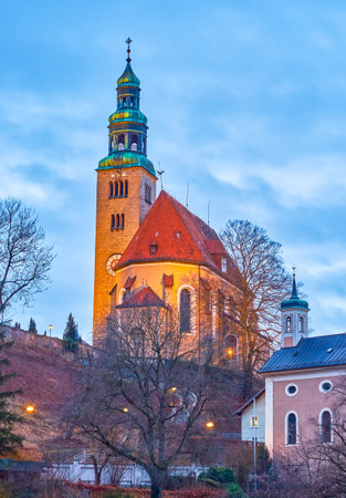 The slender Mullner Kirche with high brick bell tower standing on the Monchsberg foothill in bright evening illuminationのeditorial素材