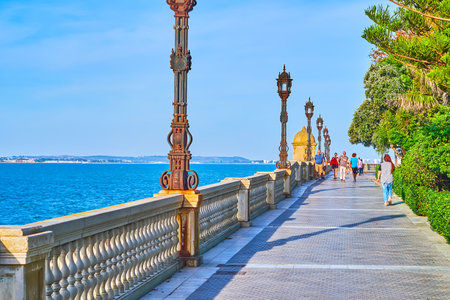CADIZ, SPAIN - SEPTEMBER 23, 2019: The oceanfront walk in Paseo de Carlos III garden with amazing views on Atlantic Ocean, lush greenery and vintage streetlights, on September 23 in Cadizのeditorial素材