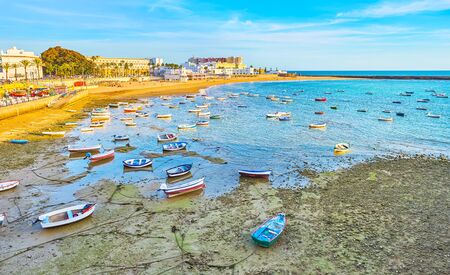 The small wooden fishing boats stands on shallow of La Caleta harbor, Cadiz, Spainの写真素材