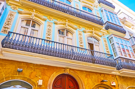 The ornate facade of historical edifice in Calle Ancha street, it's decorated with plaster reliefs, wall sculptures, lace-like cast iron balcony grills, Cadiz, Spainのeditorial素材