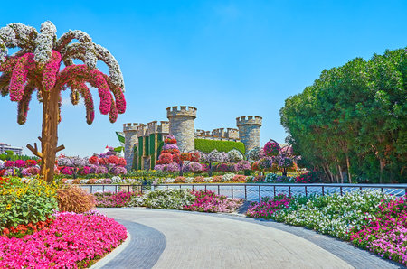 DUBAI, UAE - MARCH 5, 2020: The replica of medieval stone castle, surrounded by colored flowers of petunia and green plants in Miracle Garden, on March 5 in Dubaiのeditorial素材