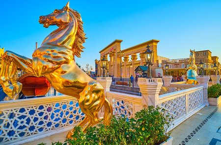 DUBAI, UAE - MARCH 5, 2020: The bridge across the canal in Global Village Dubai is decorated with sculptures of golden rearing horses, on March 5 in Dubaiのeditorial素材